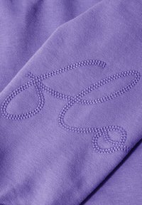 Tessuto viola con un design ricamato testurizzato caratterizzato da anelli e curve. I punti di cucitura contrastano sottilmente con il colore di sfondo.