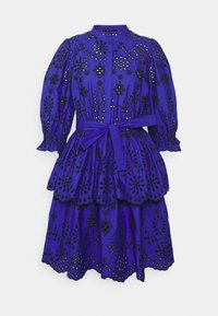 Robe en coton bleu avec broderies florales noires, présentant de longues manches bouffantes, une taille cintrée et un ourlet à plusieurs couches avec un design en forme de vagues.