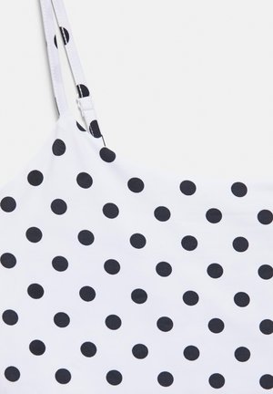 Tissu blanc à pois noirs avec bretelles fines réglables, partie d'un vêtement sans manches.