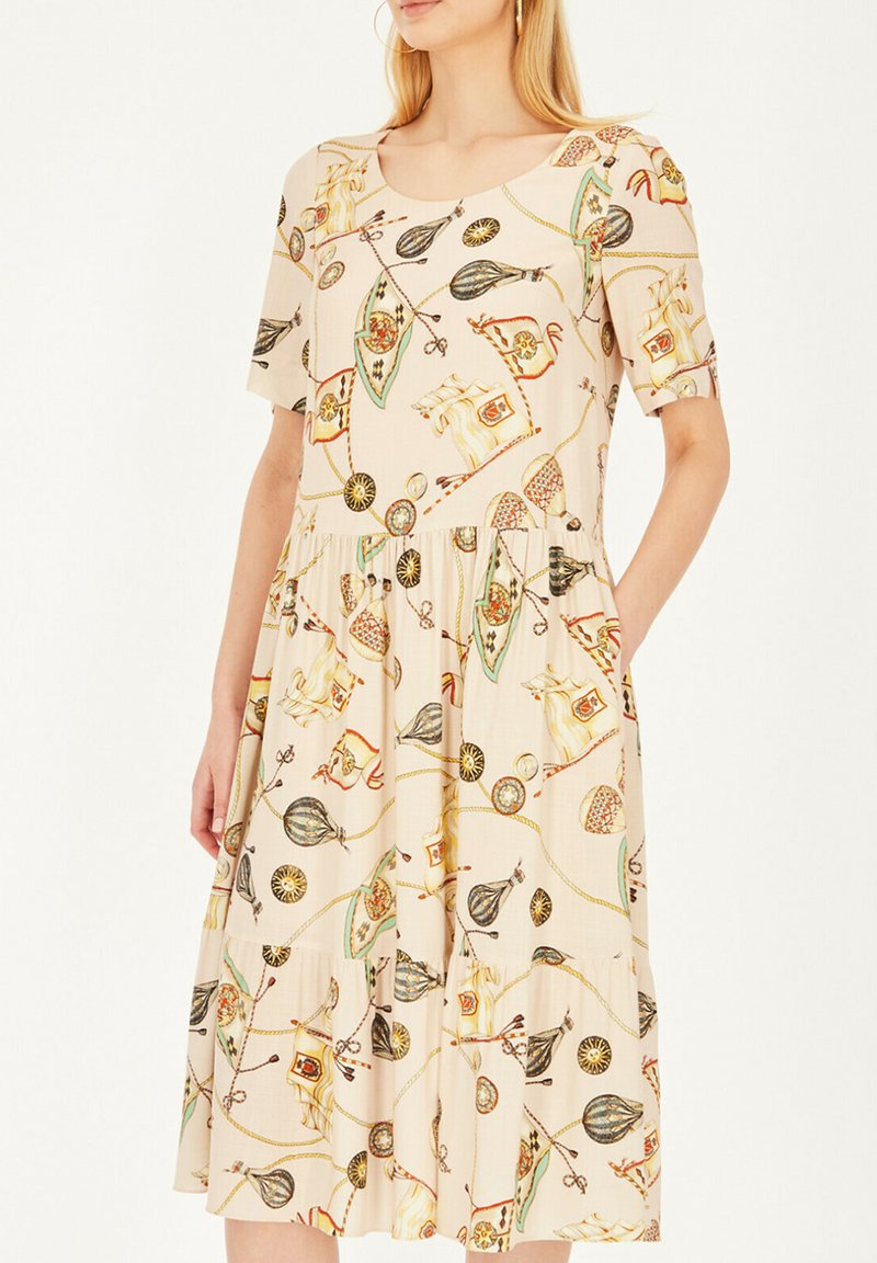 Beżowa sukienka z krótkimi rękawami, z powtarzającym się wzorem kolorowych obiektów. Projekt obejmuje kieszenie i zwiewną spódnicę.