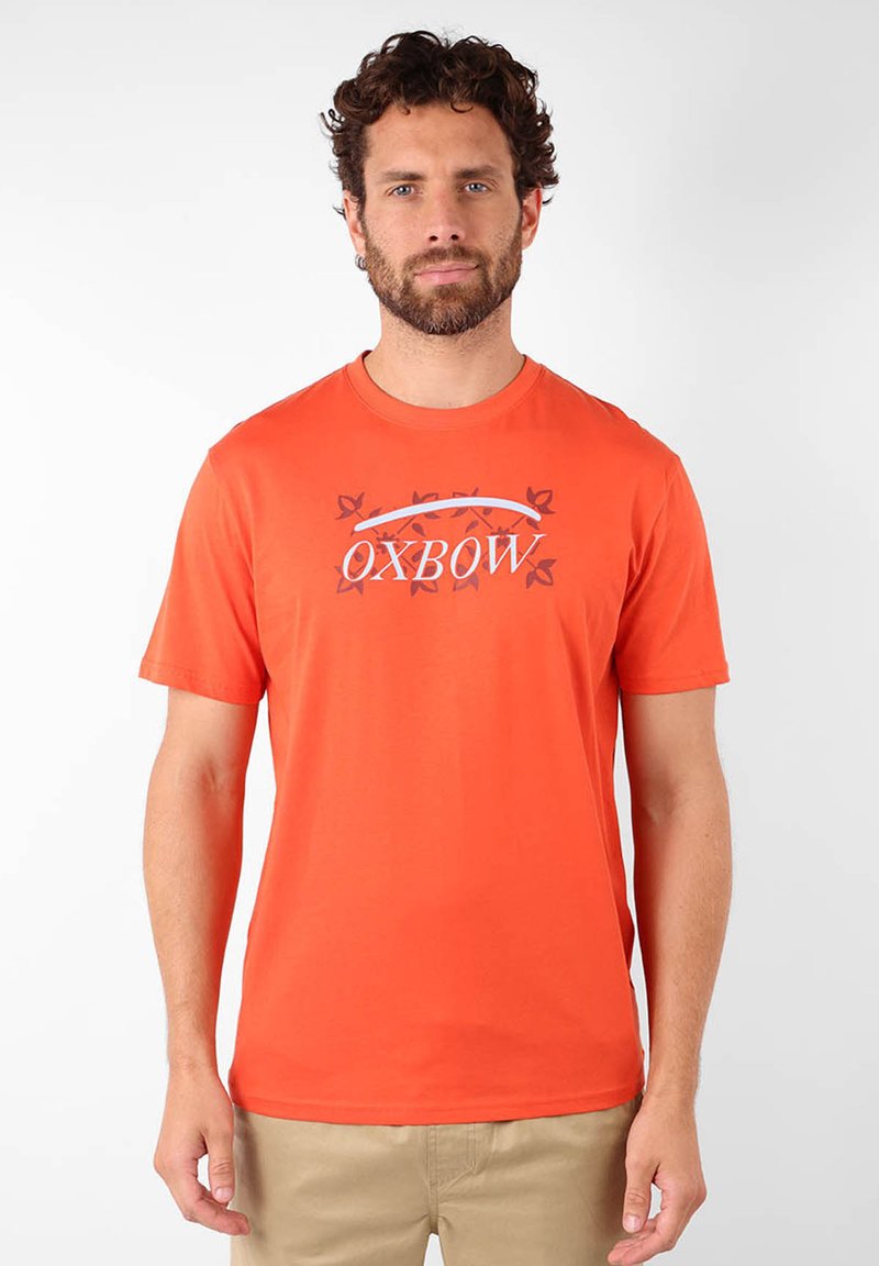 T-shirt en coton orange à manches courtes, avec un logo graphique « OXBOW » et un motif minimal dans une teinte contrastante.