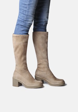 Botas de ante beige hasta la rodilla con taco cuadrado, que presentan un acabado suave y punta redondeada. El diseño es elegante y ajustado.