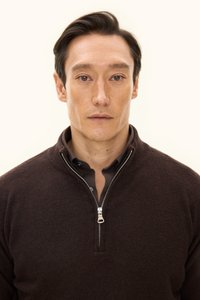 Brun zip-up tröja gjord av mjukt tyg, med hög krage och silvrig dragkedja, bärs över en svart skjorta.