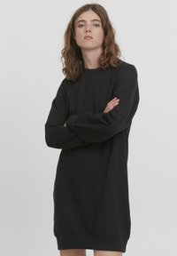 Abito felpa nero realizzato in tessuto morbido, con collo rotondo, maniche lunghe con leggero gonfiore e vestibilità comoda. Senza motivi o dettagli.