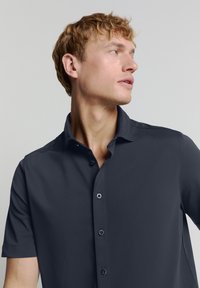 Korte mouwen shirt in donkergrijs, gemaakt van een gladde stof. Heeft een button-down kraag en zwarte knopen, met een ontspannen pasvorm en zonder patronen.