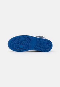Semelle de sneaker Nike, en caoutchouc bleu, texturée avec des motifs circulaires et linéaires, comportant un logo circulaire et des rainures pour la traction.