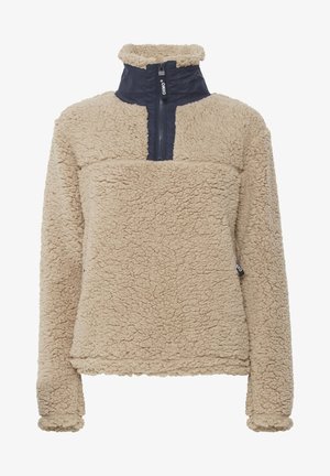 Beige fleece-tröja med en fyrdelad dragkedja, hög krage och marinblå panel i den övre fronten, med textil som är strukturerad och mjuk.