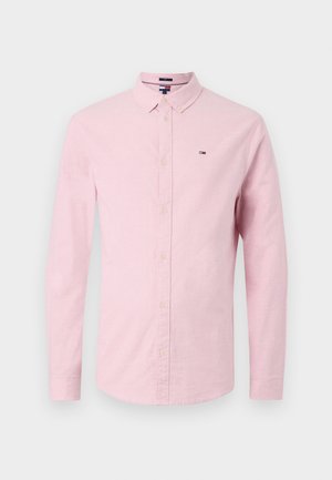 Chemise boutonnée à manches longues rose avec une texture douce. Elle présente un col classique, des boutons à l'avant et un petit logo sur la poitrine.