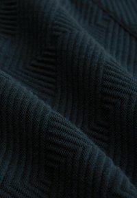 Tissu texturé foncé arborant un motif en chevrons avec des stries subtiles, affichant des nuances de bleu profond et de noir. Texture douce et tissée.