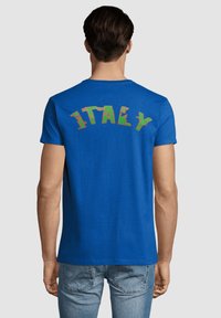 Camiseta de algodón azul con un gráfico colorido de "ITALIA" en la parte de atrás. Manga corta y cuello redondo, mostrando una textura suave.