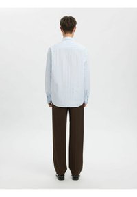 Lyseblå og hvitstripet skjorte med lange ermer, avslappet passform og bakre legg, kombinert med mørkebrune, vide bukser.