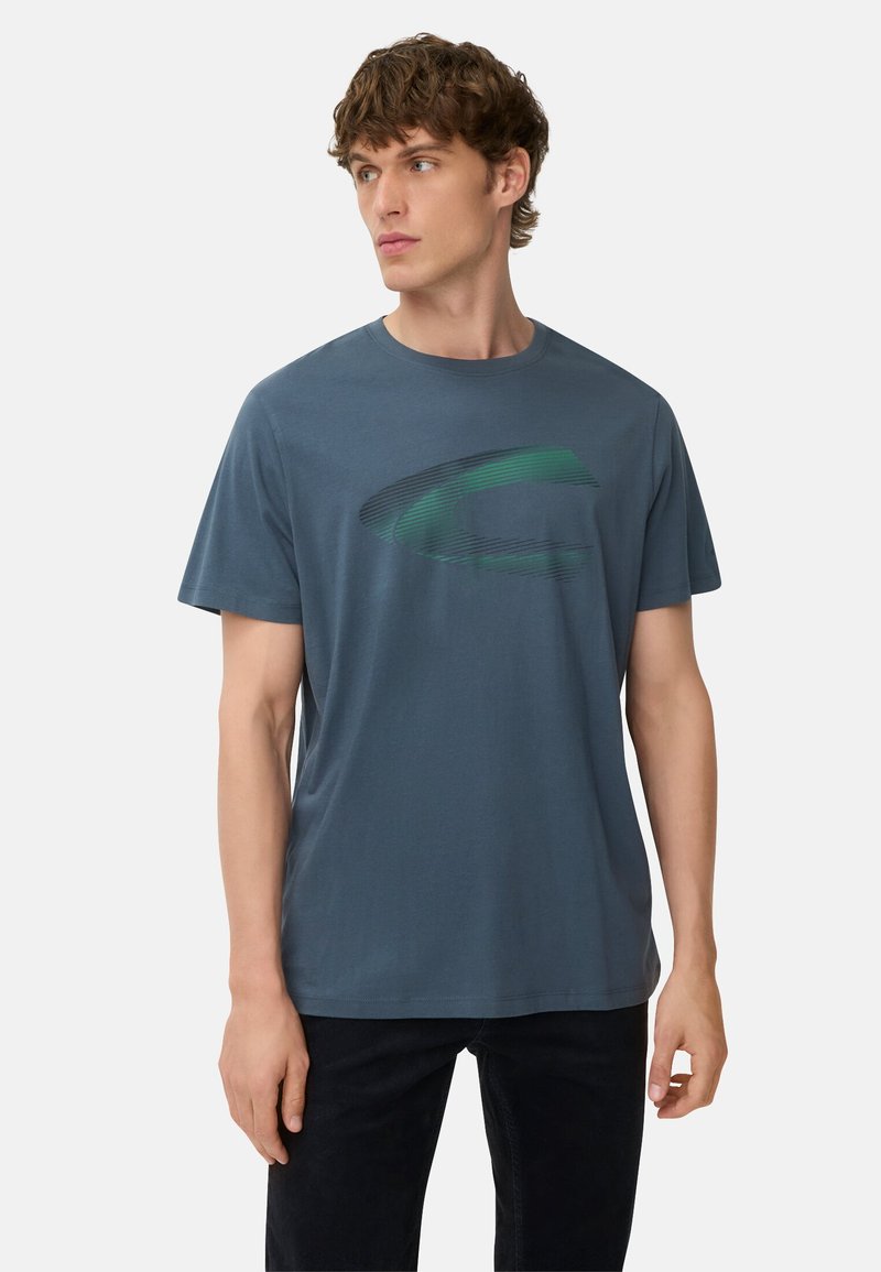 Blå bomulds t-shirt med kortærmet design. Har et grønt C-logo som grafik på fronten. Enkel rund hals og afslappet pasform.