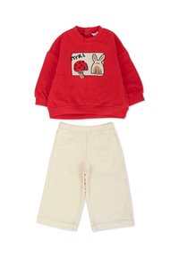 Czerwona bluza z nadrukiem grzyba i królika, zestawiona z kremowymi spodniami o szerokich nogawkach. Miękka tkanina, fason typu pulower oraz elastyczna talia.