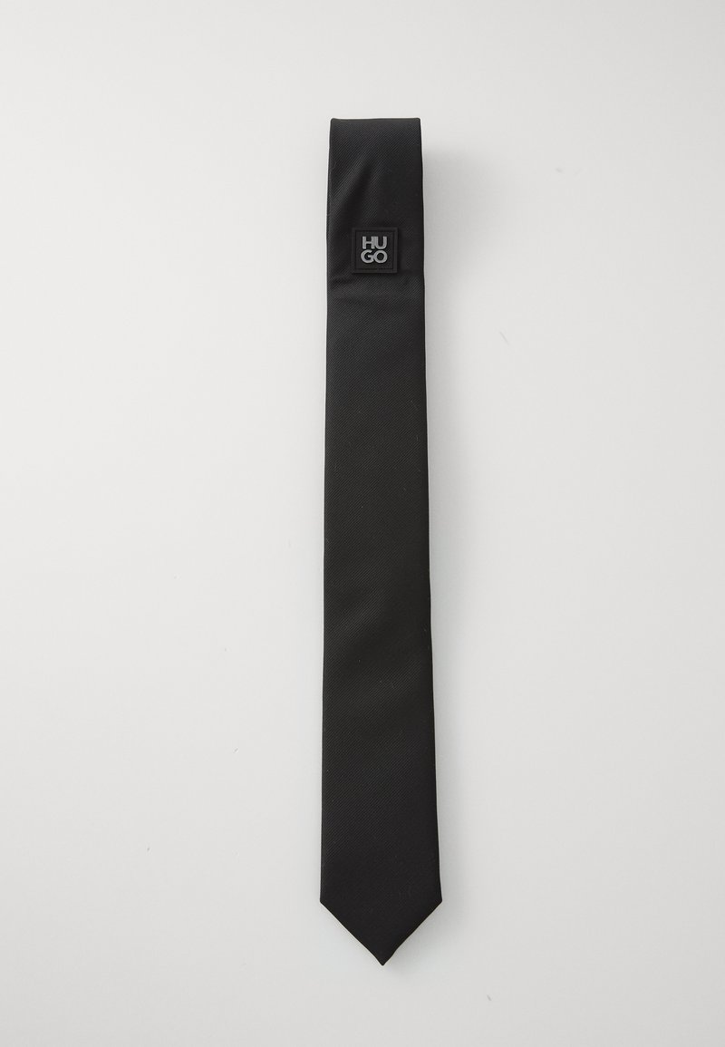 Culoare neagră, cravată dintr-un material neted, cu o textură subtilă, dotată cu un mic accent logo negru aproape de partea superioară.