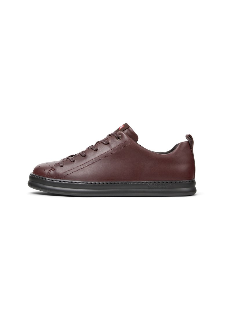 Sneaker in pelle marrone con profilo basso, punta arrotondata e dettagli perforati. Suola in gomma nera con cuciture visibili e etichetta sul tallone.