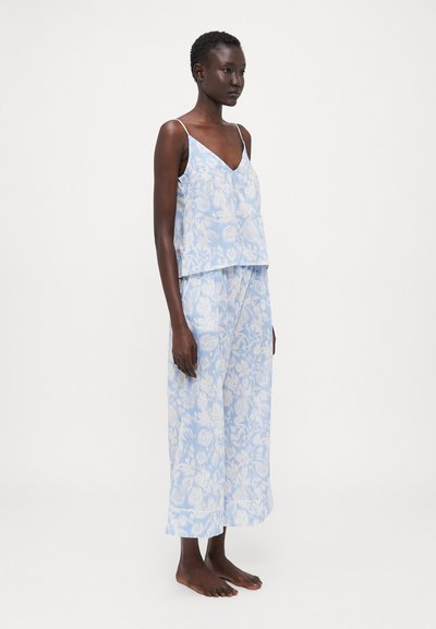 Conjunto de duas peças com padrão floral em azul claro, apresentando uma blusa sem mangas com decote em V e calças largas e fluidas com um corte descontraído.