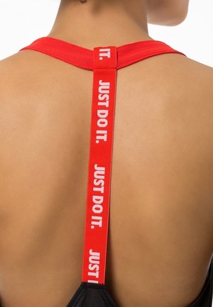 Zwarte sportbeha met een rode band en witte letters "JUST DO IT." Het ontwerp is minimalistisch en benadrukt functionaliteit en comfort.