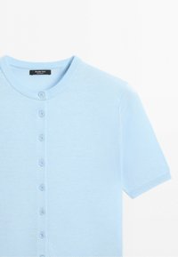 Lichtblauwe cardigan met korte mouwen, ronde hals en een rij van zeven bijpassende knopen aan de voorkant.