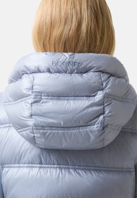 Helles blaues Puffermantel mit hochgeschlossenem Kragen, mit gesteppte Abschnitten und dem Wort "BOGNER", das auf die Rückseite der Kapuze gestickt ist.