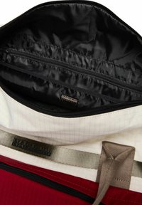 Zaino bianco e rosso aperto che mostra l'interno nero con tasca con zip e tracolla beige con logo Napapijri.