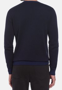 Pull en maille côtelée bleu marine avec col rond et manches longues, présentant un tissu texturé ainsi qu'une taille et des poignets contrastants.