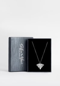 Silverhalsband med fläktformad hänge, med utskurna ränder, som visas i en svart sammetsklädd låda med en metallisk grå yta.