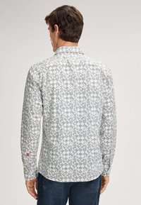 Witte lange mouwen overhemd met een geometrisch blauw patroon, knoopkraag en merkaccenten op de mouwmanchetten. Gestructureerde stof.