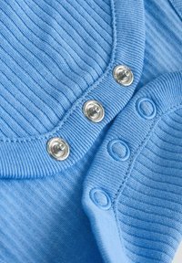 Plava rebrasta tkanina s metalnim kopčama na drukere i odgovarajućim plavim plastičnim drukerima na izrezu odjeće.