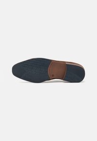Semelle de chaussure avec une section intermédiaire en cuir marron, un fond en caoutchouc bleu foncé texturé et un motif de semelle pour une meilleure adhérence.