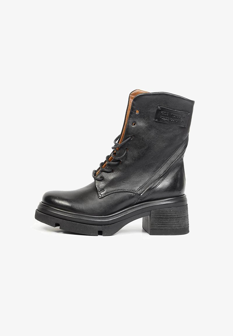 Bottine en cuir noir avec talon épais, lacets à l'avant, fermeture éclair latérale et un patch rectangulaire cousu près du haut.