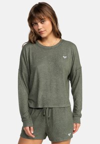 Olive green knit sweatshirt with long sleeves and a round neck, paired with matching shorts featuring an adjustable drawstring and logo detail.