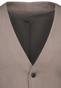 Καφέ γιλέκο με V-λαιμόκοψη, κατασκευασμένο από απαλό ύφασμα. Διαθέτει μαύρη φόδρα και ένα μαύρο κουμπί.