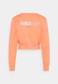 Zkrácená mikina jasně oranžové barvy. Vybavena kulatým výstřihem, dlouhými rukávy a potiskem "NIKE AIR" v bílé barvě na zadní straně.