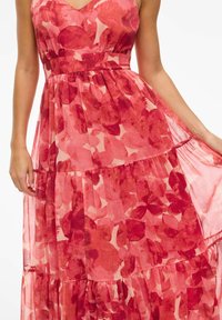 Robes maxi dans des nuances de rouge et de rose avec un motif floral abstrait, un design à volants, un décolleté en V et un tissu léger.