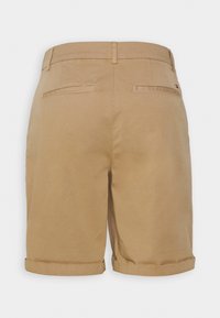 Pantaloni corti chinos beige con orlo arrotolato, dotati di due tasche posteriori e dettagli del logo del marchio discreti. Tessuto in cotone liscio e vestibilità sartoriale.