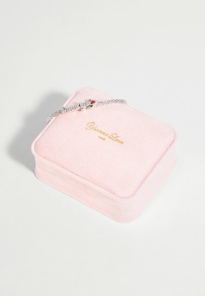 Bracelet chaîne en argent avec une petite figurine tenant un cœur rouge reposant sur une boîte à bijoux en velours rose avec un texte doré.