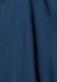 Textuur van blauwe stof met een gaaspatroon, met een roosterachtig ontwerp. Het materiaal lijkt lichtgewicht en ademend.