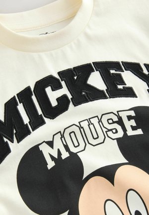 Cream-colored T-shirt made of cotton. Features bold black "MICKEY MOUSE" text and a graphic of Mickey's face, with a smooth texture.