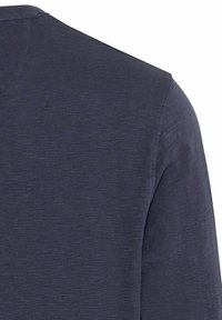 Dunkelblaues Langarmhemd aus strukturiertem Stoff, mit Rundhalsausschnitt und leicht taillierter Form. Nähtliche Details sind sichtbar.