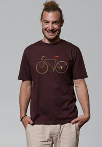 Donker kastanjebruine katoenen t-shirt met een minimalistische fiets graphic in geel en rood. Korte mouwen, ronde hals en een relaxte pasvorm.