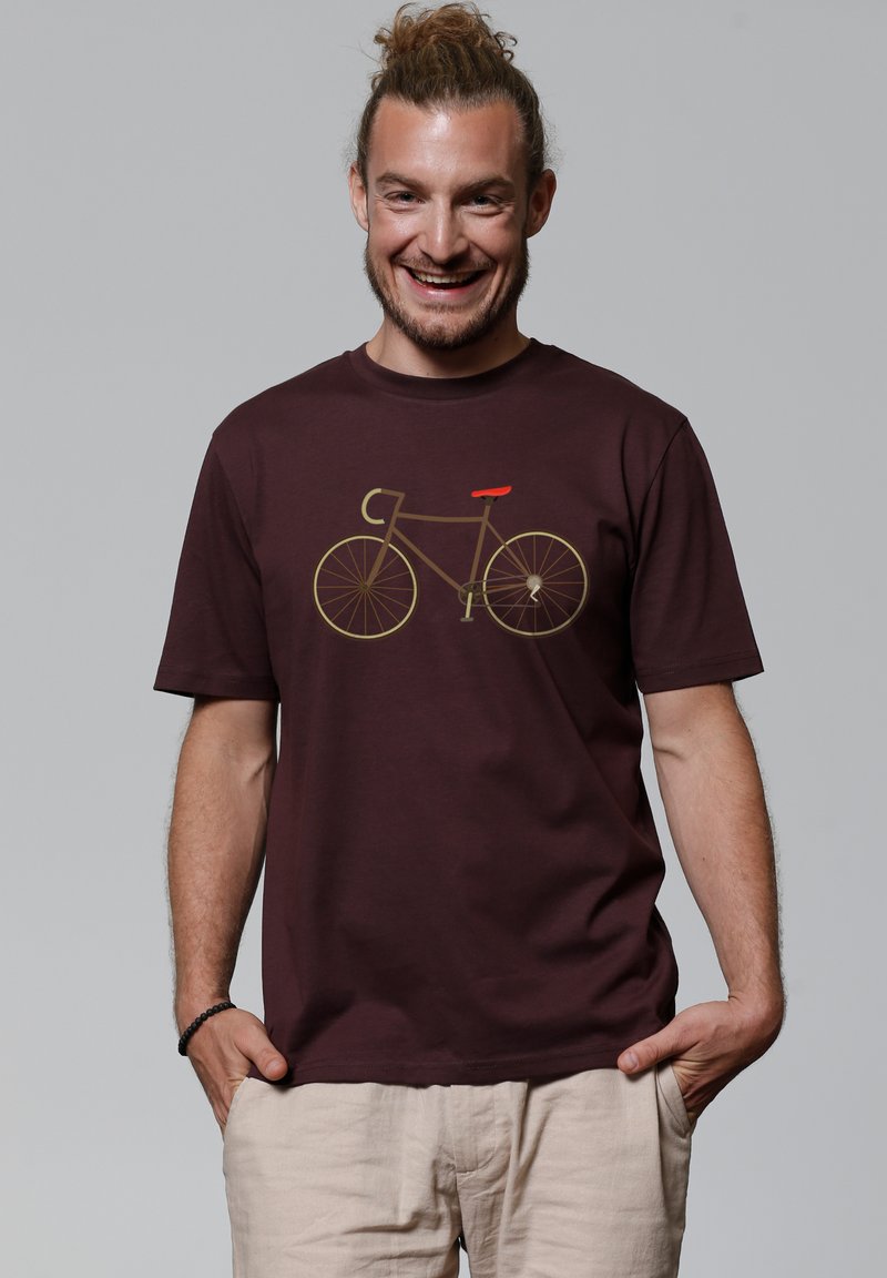 Donker kastanjebruine katoenen t-shirt met een minimalistische fiets graphic in geel en rood. Korte mouwen, ronde hals en een relaxte pasvorm.