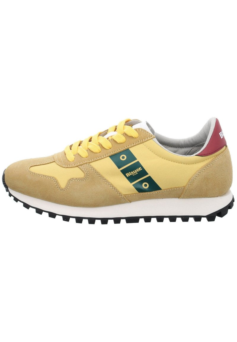 Scarpa da corsa gialla e beige con suola nera, lacci gialli, linguetta rossa sul tallone e striscia verde con logo sul lato.