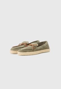 Espadrillas in suede verde con una spessa suola in juta intrecciata e lacci in pelle marrone, caratterizzate da una punta arrotondata e un interno imbottito per il massimo comfort.