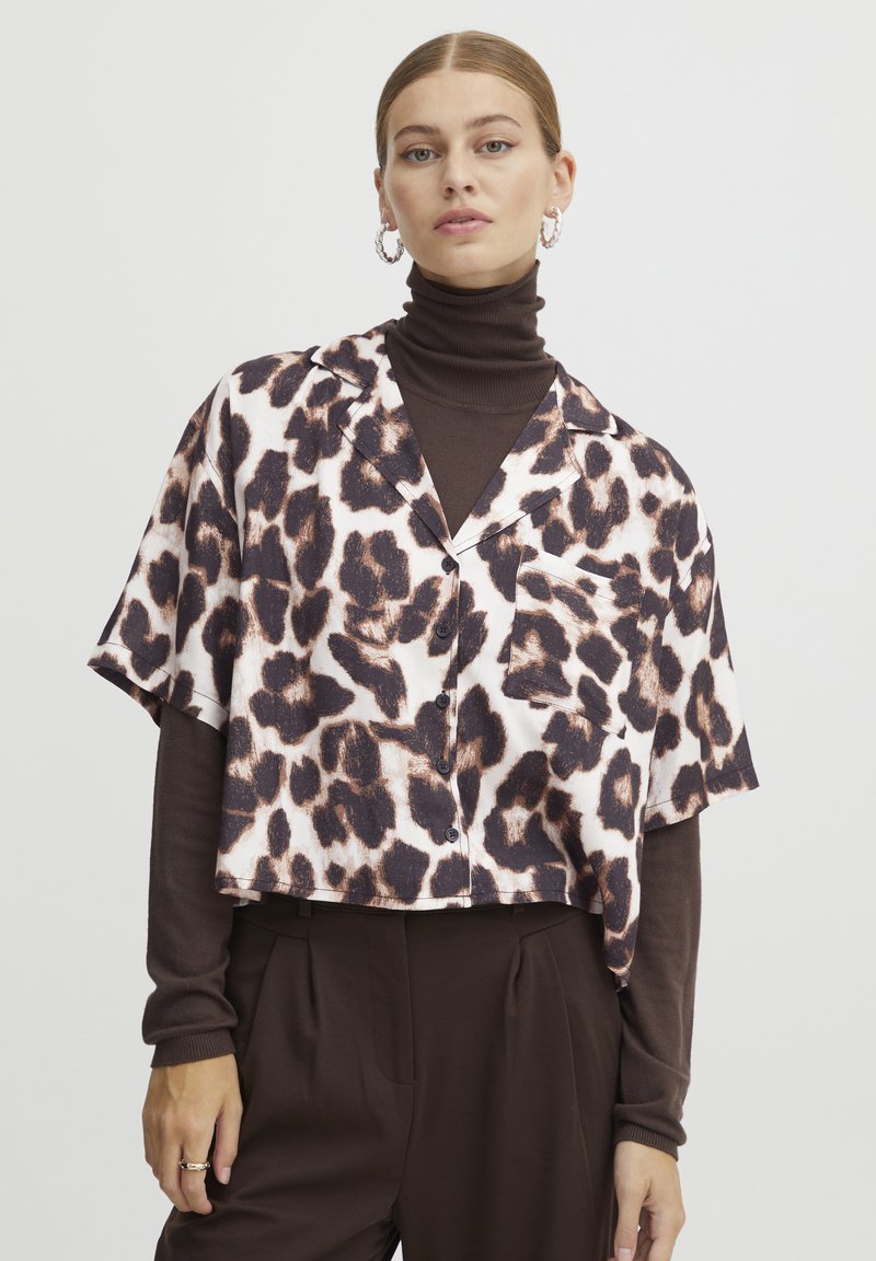 Afklippet button-up skjorte med leopardprint i sort og brun på en lys baggrund; kortærmet, letvægts stof og en lomme.