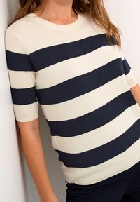 Gestreifter Strickpullover in Marineblau und Creme mit rundem Ausschnitt und kurzen Ärmeln, gestaltet mit horizontalen Streifen und einer weichen Textur.