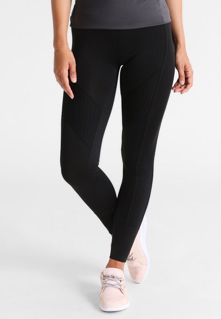 Zwarte sportlegging met textuur en een diamantpatroon op de bovenbenen, met een aansluitend ontwerp. Gecombineerd met lichtroze hardloopschoenen.