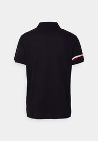 Černé polo tričko s klasickým límcem, krátkými rukávy a červenobílými pruhovanými akcenty na okrajích rukávů. Hladká textura.