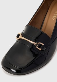 Loafers din piele lacuită neagră cu vârf pătrat, având un detaliu cu cataramă în ton de aur și accente de cusătură pe marginea de sus.