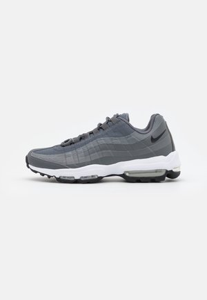 Sneaker Nike Air Max 95 grigia e nera con suola bianca e ammortizzazione ad aria visibile nel tallone e nella parte anteriore del piede su sfondo bianco.