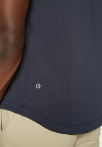 Marineblaue Sportshirt aus strukturiertem Stoff, mit kleinem Logo am Saum, Rundhalsausschnitt und kurzen Ärmeln.